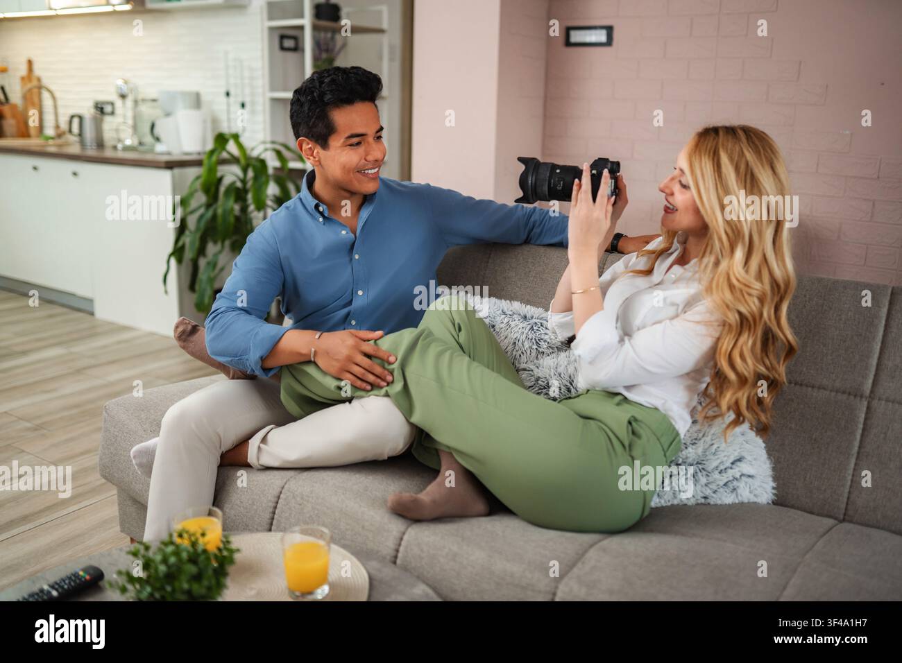 Coppia che si rilassa a casa, godendosi l'hobby della fotografia insieme Foto Stock