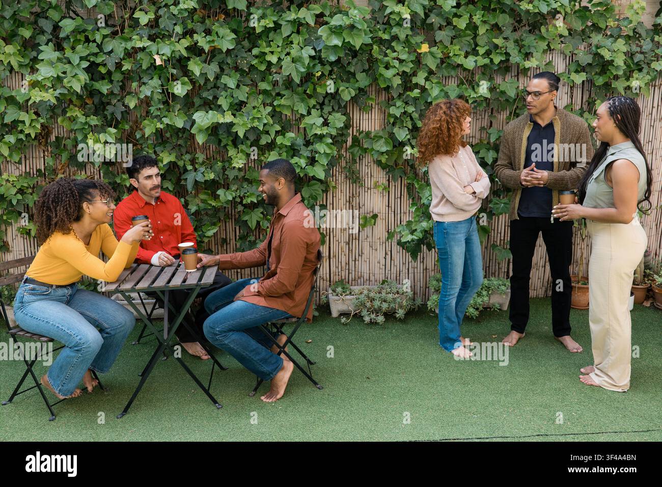 Amici diversi che godono di caffè e conversazioni all'aperto Foto Stock