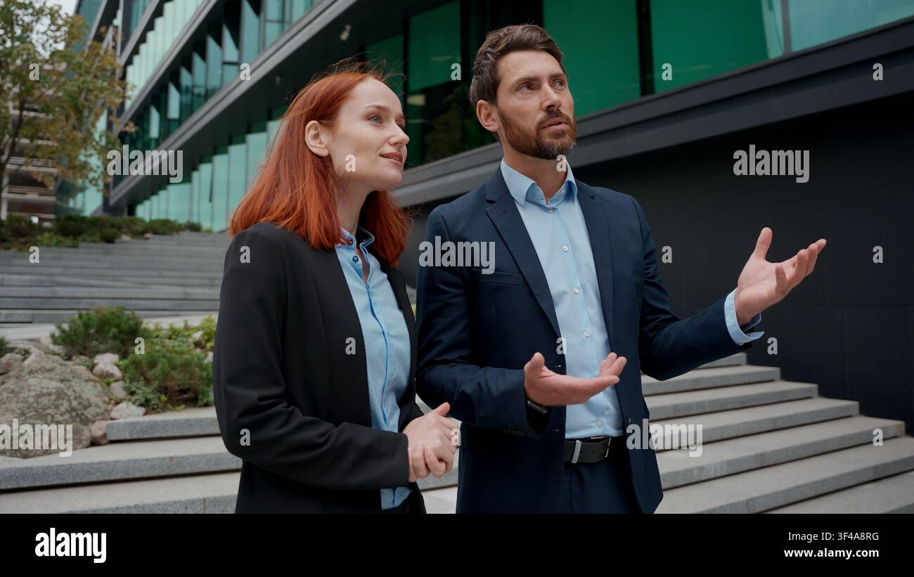 Due partner commerciali caucasici, donna e uomo, si incontrano in città, si stringono la mano e discutono di uomini d'affari edificio per uffici imprenditori uomo d'affari adulto Foto Stock