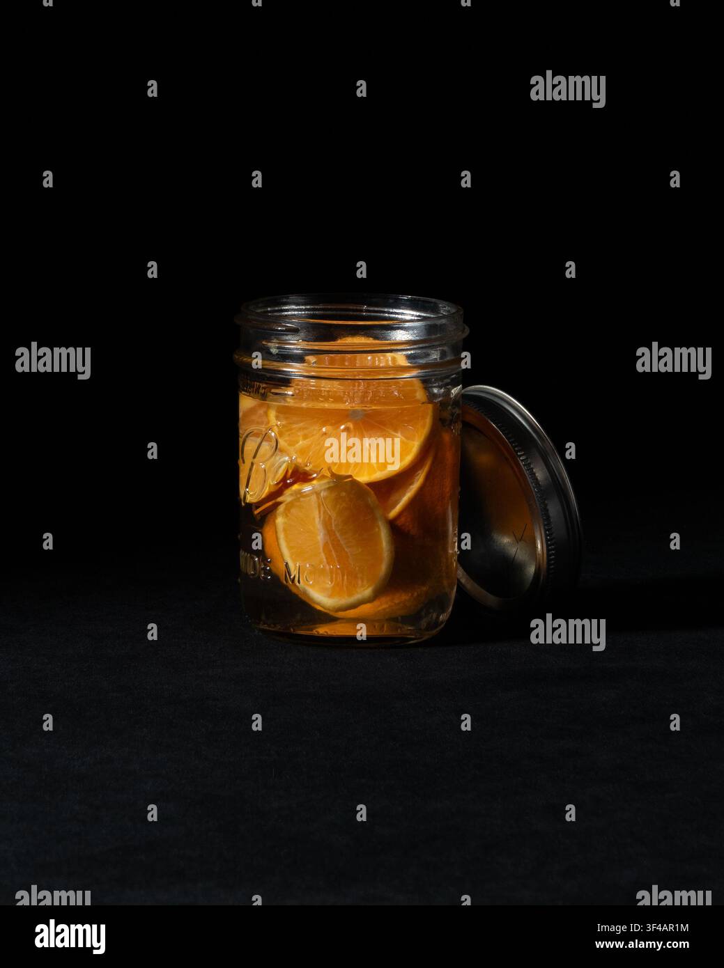 Ingredienti per un miscelatore di cocktail: barattolo Mason pieno di fette di arancia che macerano in sciroppo semplice. Foto Stock