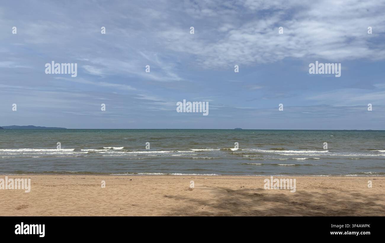 Morbide onde su una spiaggia sabbiosa sotto un cielo nuvoloso a Pattaya, Thailandia - Immagine stock catturata con smartphone
