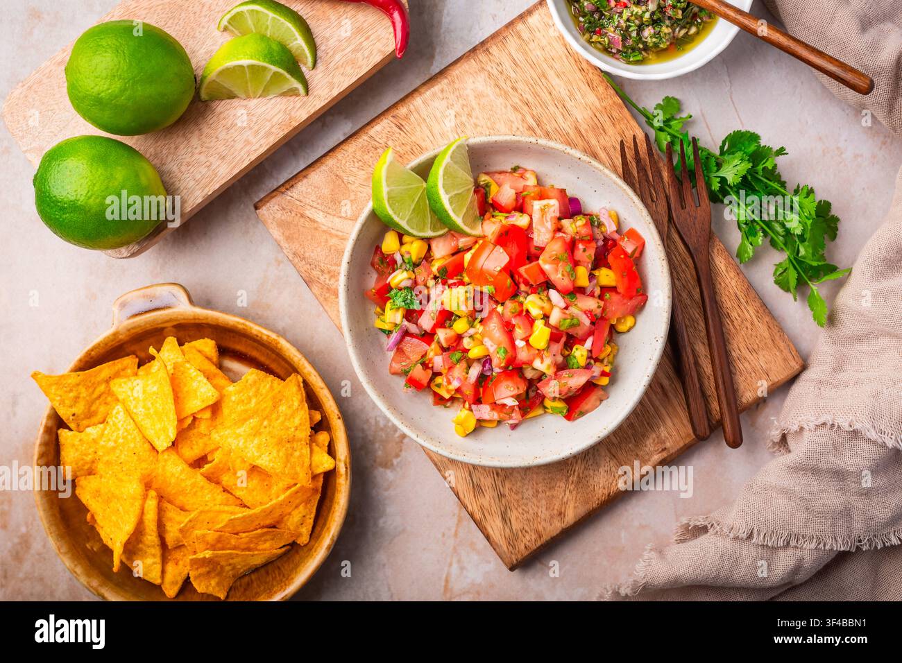 Pico de gallo appena preparato con mais e spicchi di lime servito con chips di tortilla Foto Stock