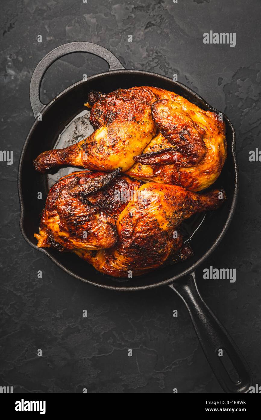 Cosce di pollo arrosto succose e croccanti in una padella di ghisa Foto Stock