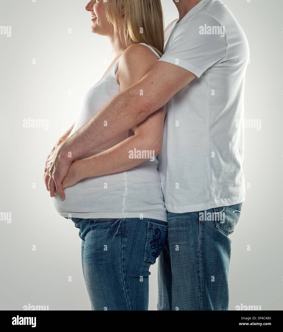 L'uomo abbracciando la donna incinta da dietro Foto Stock