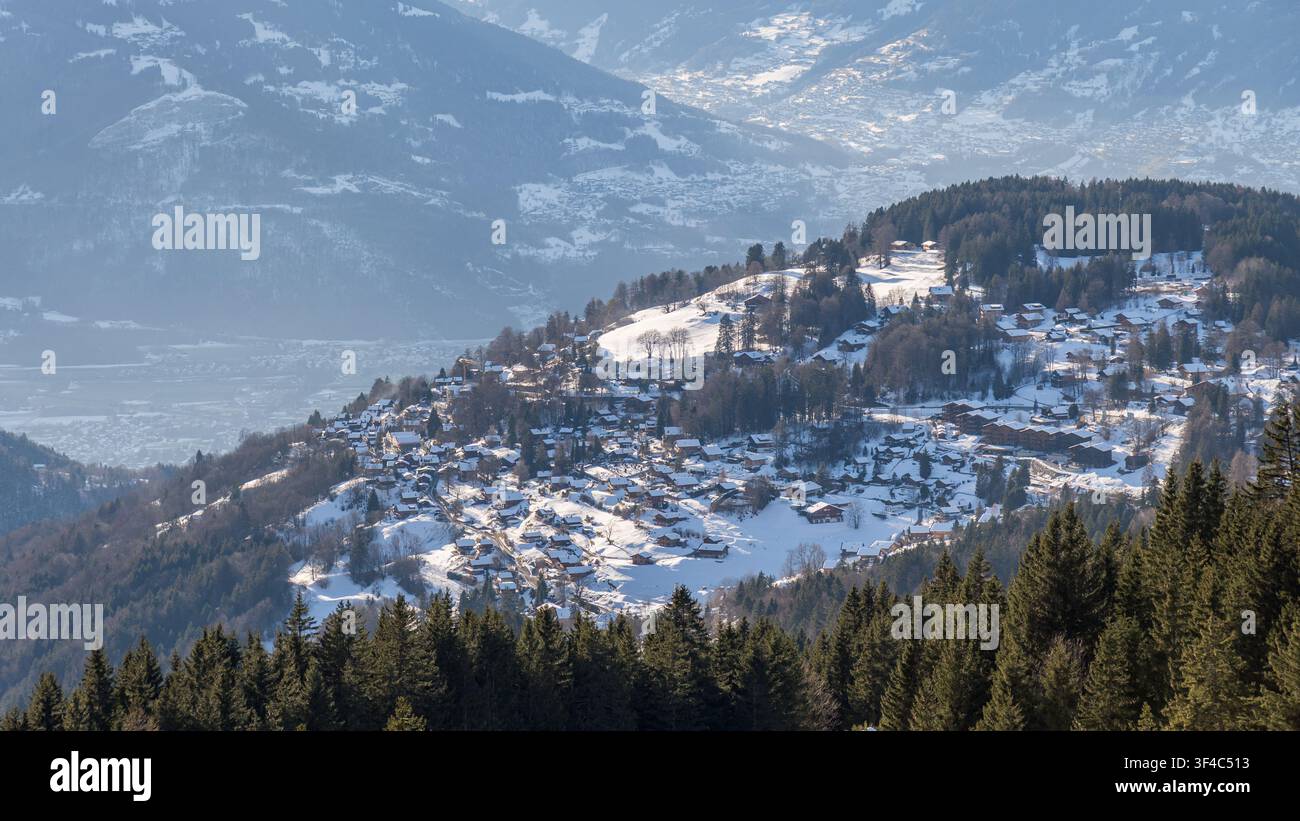Villaggio alpino con case incastonate tra montagne innevate Foto Stock