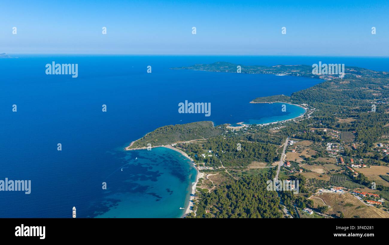 Una vasta prospettiva aerea mostra promontori boscosi, insenature turchesi protette, case sparse e il profondo mare Egeo blu lungo Golden Beach a Foto Stock