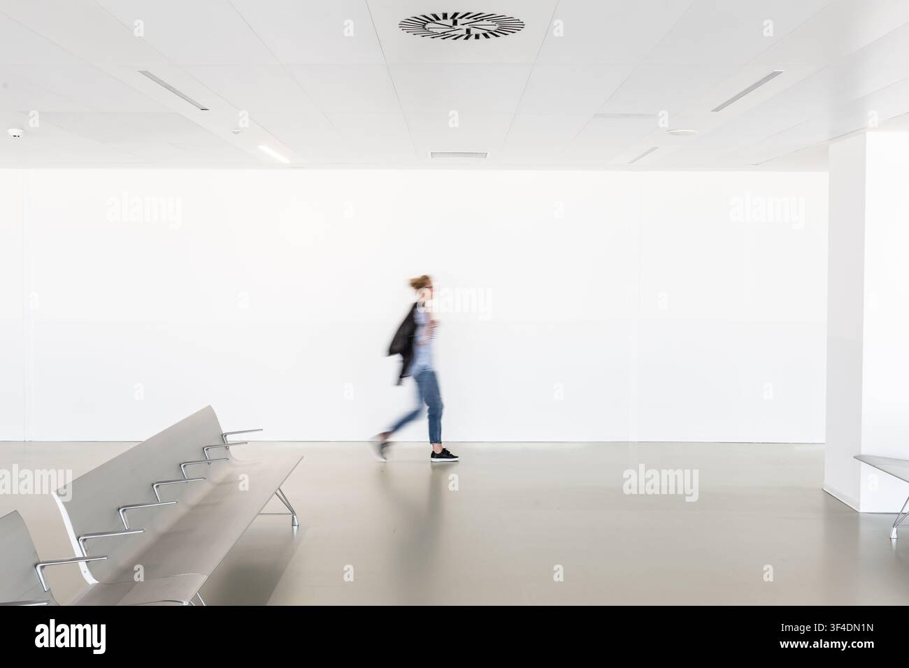 Motion Blur di donna a piedi la contemporanea vuoto bianco corridoio. Foto Stock
