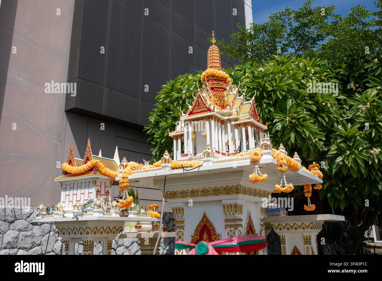 Santuario all'aperto tradizionale thailandese decorato con ghirlande di fiori di crisantemo giallo e offerte Foto Stock