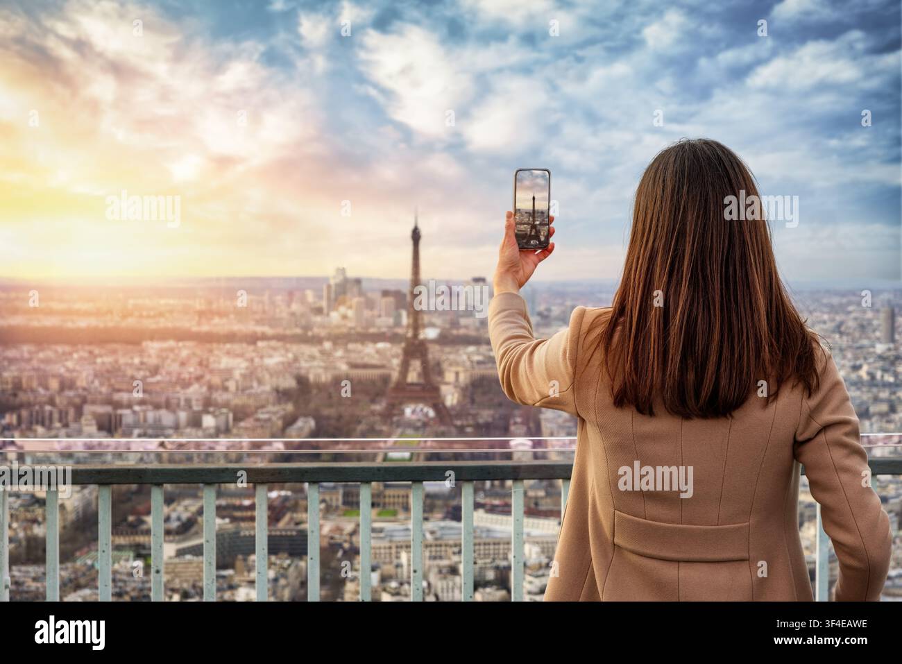 Una turista scatta foto con il telefono dalla skyline di Parigi, Francia, durante l'ora del tramonto Foto Stock