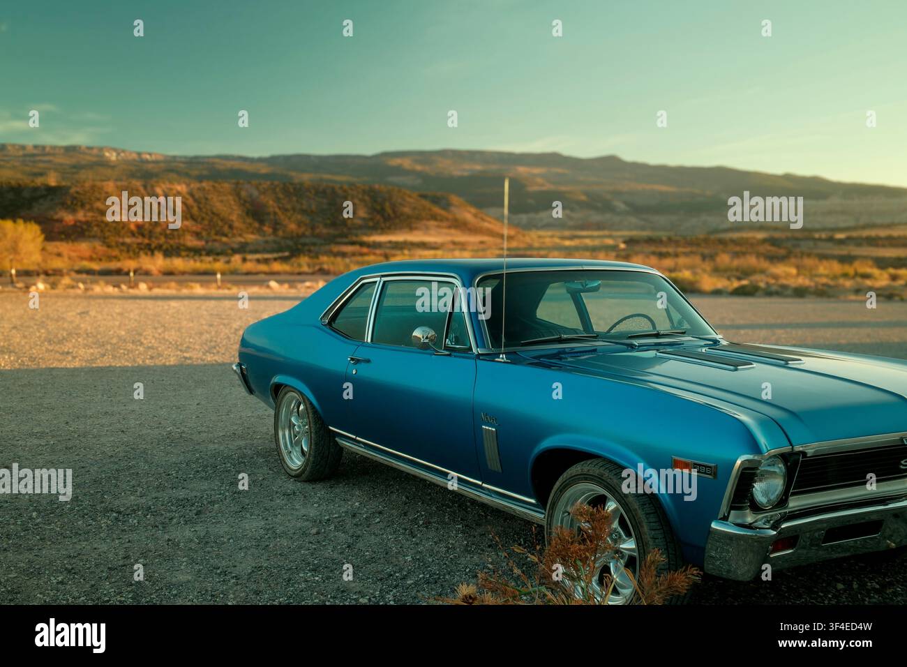 Classica Chevrolet Nova blu parcheggiata accanto alle scogliere rosse vicino al Capitol Reef National Park a Torrey, Utah, USA Foto Stock