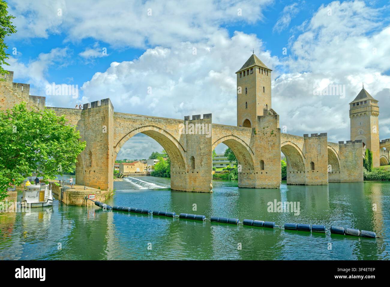 Incrociatore da diporto che si avvicina alle chiuse del ponte Valentré sul fiume Lot a Cahors nella regione Occitania del sud della Francia. Foto Stock