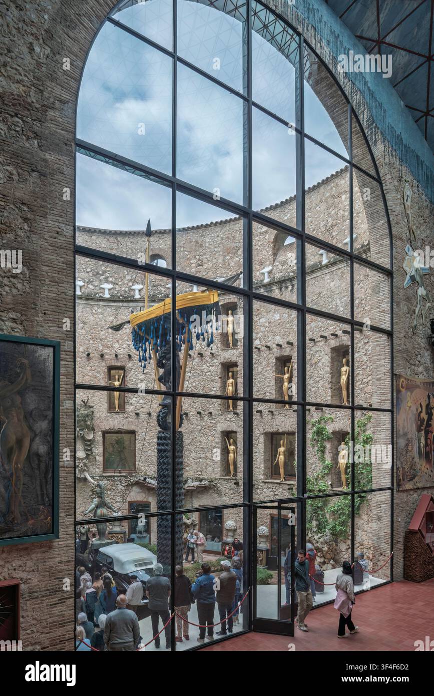Vista attraverso una grande finestra del cortile del Teatro-Museo Dalí a Figueres, in Spagna, con sculture surrealiste e manichini dorati. Foto Stock