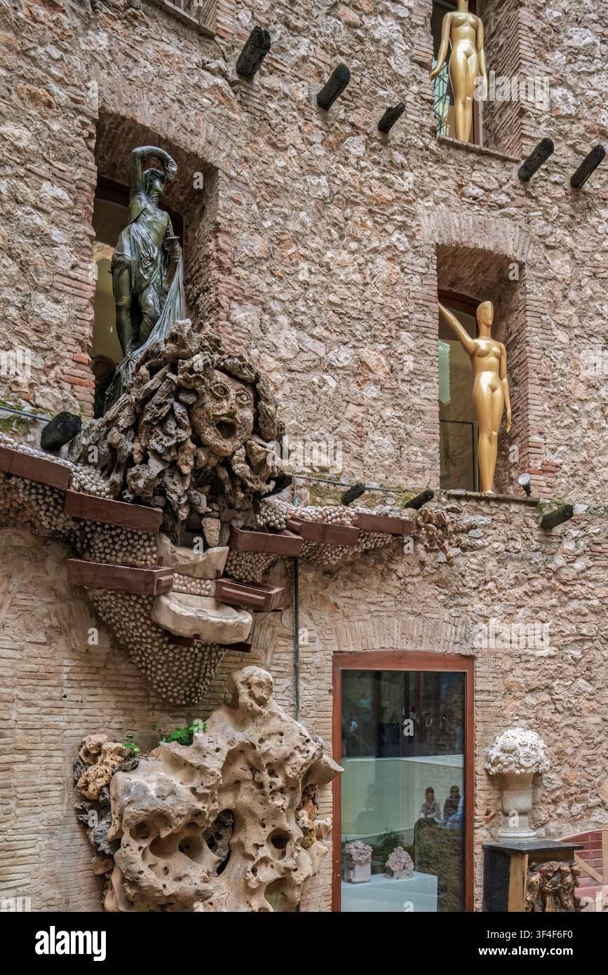Cortile surrealista del Teatro-Museo Dalí a Figueres, in Spagna, con sculture grottesche e manichini dorati su muri di pietra. Foto Stock