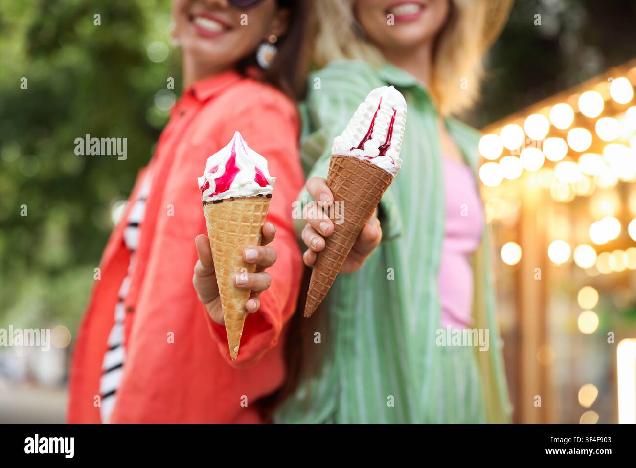 Amici felici che mostrano coni di waffle con deliziosa gelata nel parco, messa a fuoco selettiva Foto Stock