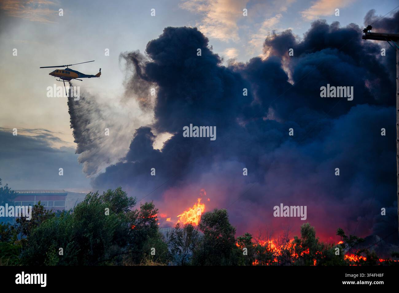 Un elicottero antincendio sgancia acqua sul incendio boschivo di Oraiokastro a Salonicco il 5 luglio 2026, evidenziando la gravità della siccità e dei cambiamenti climatici Foto Stock
