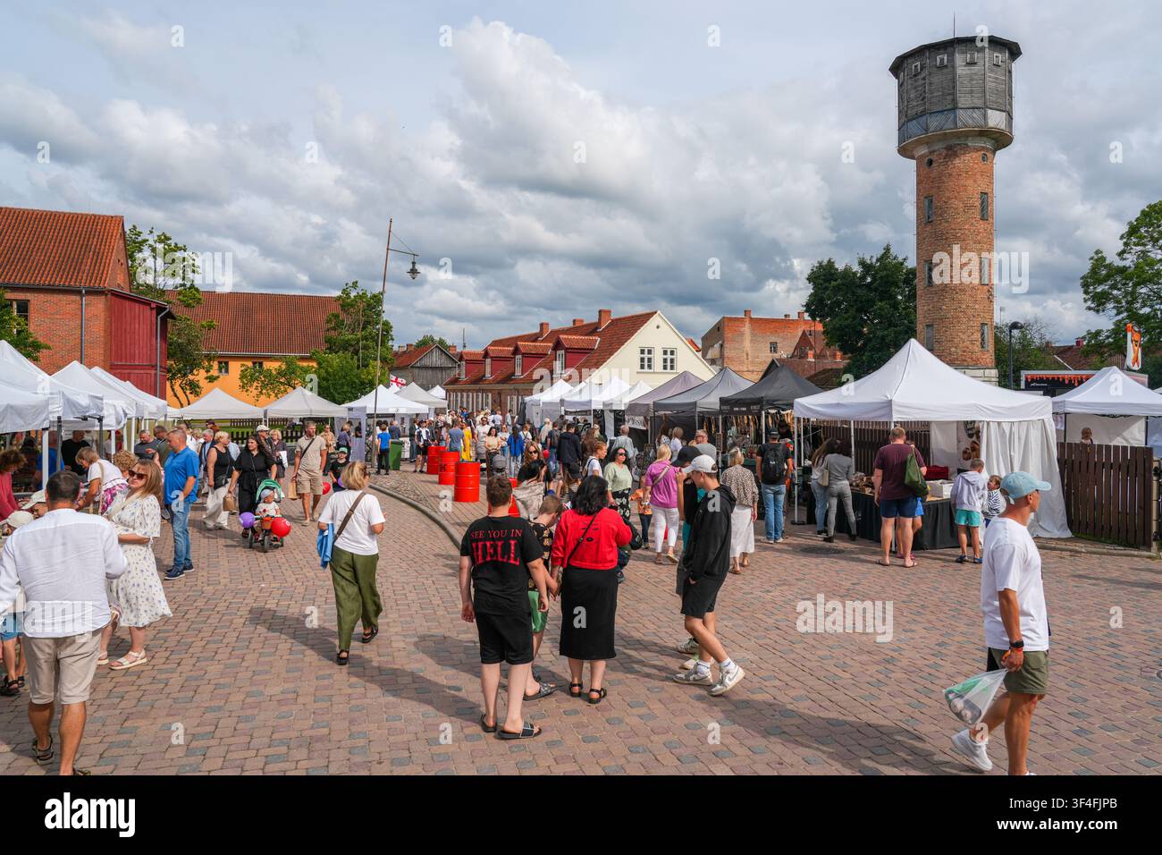 Kuldiga, Lettonia - 25 luglio 2026: Mercato del festival della vecchia città e torre dell'acqua storica in una giornata estiva Foto Stock