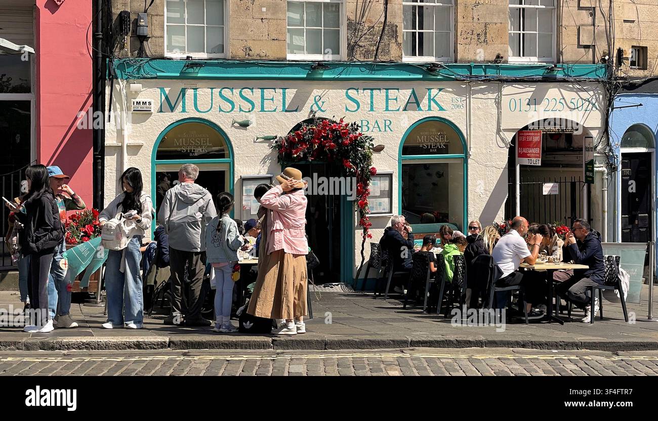 Clienti che mangiano all'aperto al bar Mussel & Steak, Grassmarket, Edimburgo, Scozia - Immagine stock catturata con smartphone