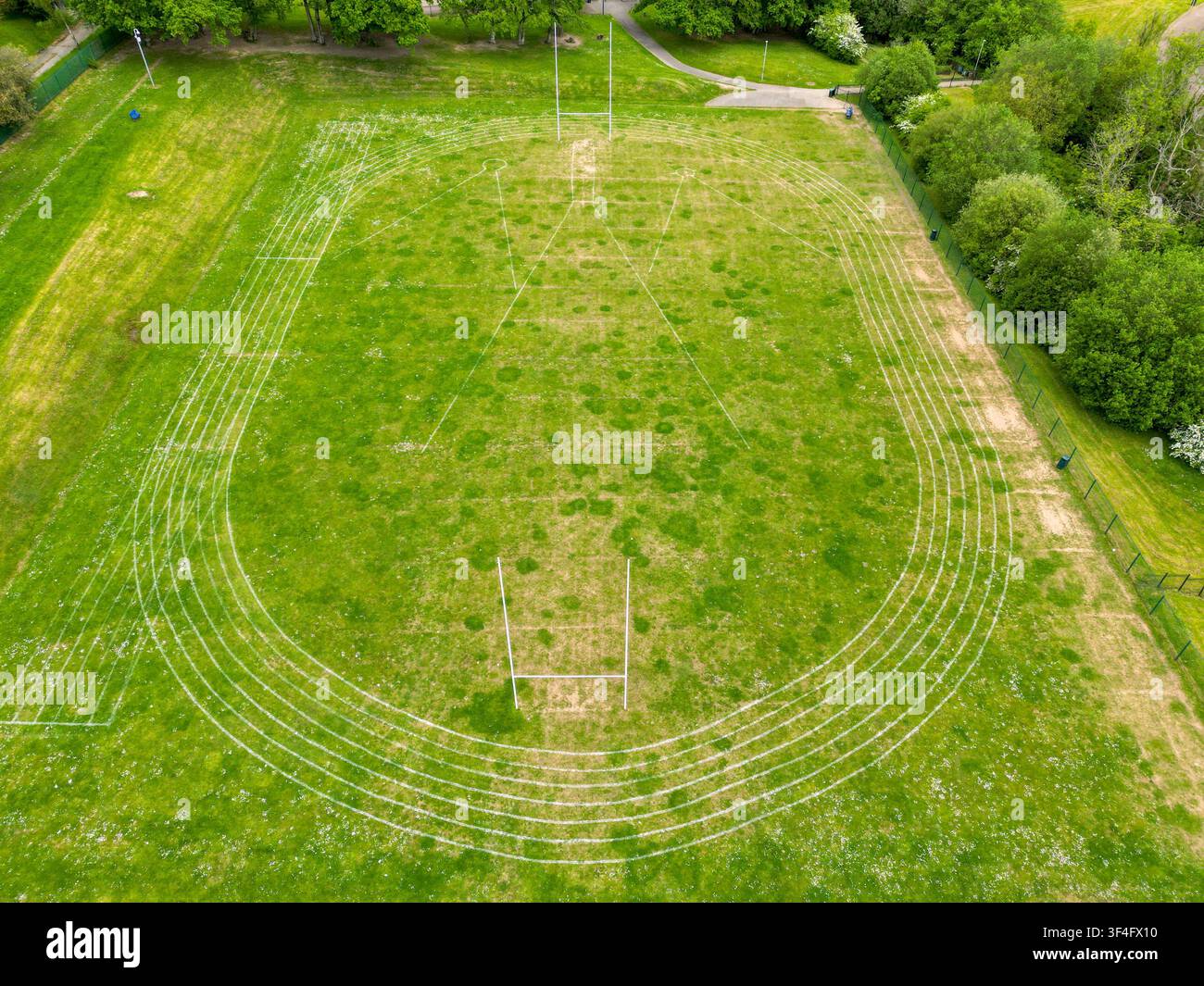 Vista a droni di un campo da rugby scolastico con una pista di atletica segnata intorno. Nessuna persona. Foto Stock