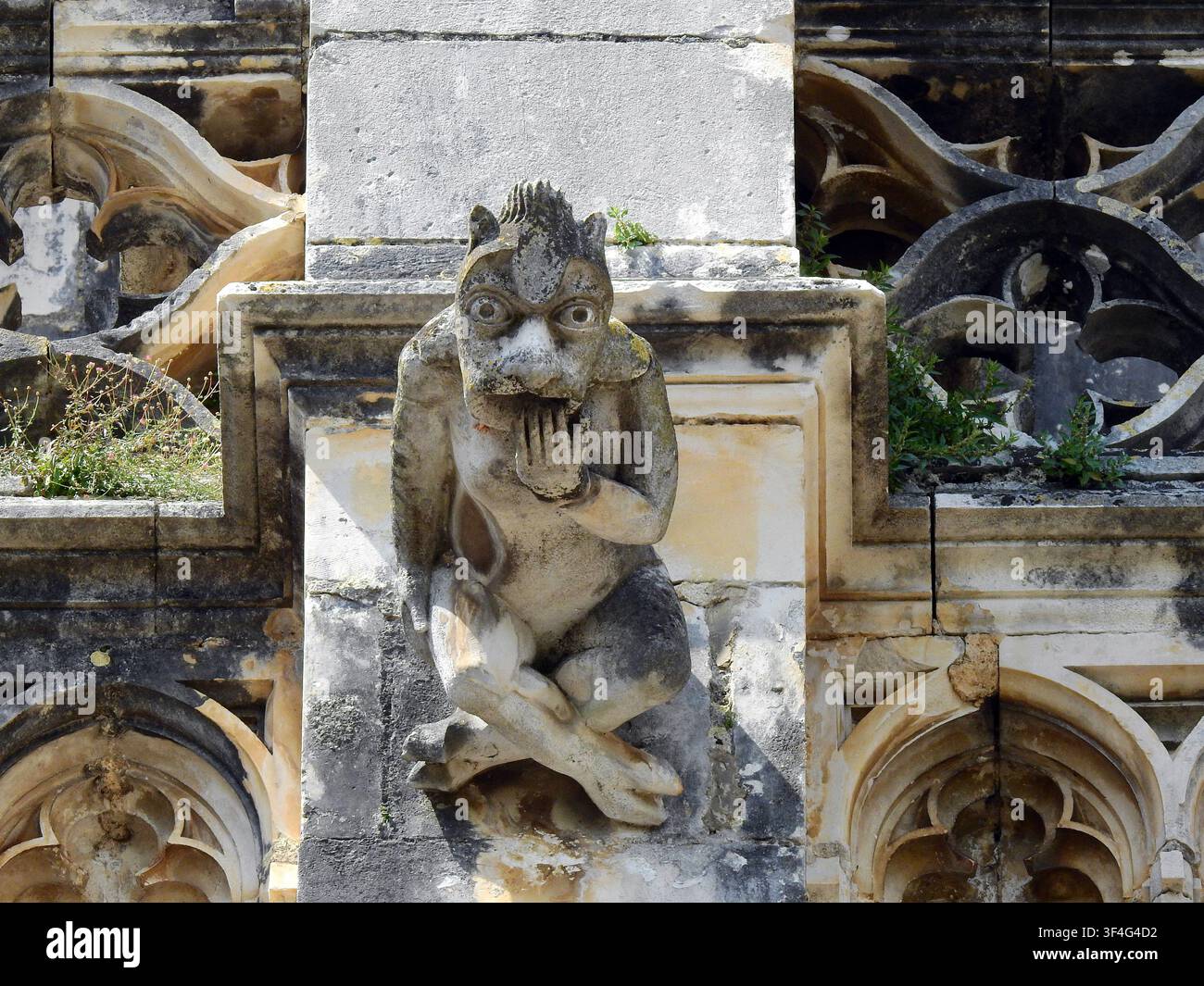 Gargoyle in pietra erosa che sporgono dalle mura in pietra gotiche e manueline del Monastero di Batalha in Portogallo, scolpite a forma di creature fantastiche Foto Stock