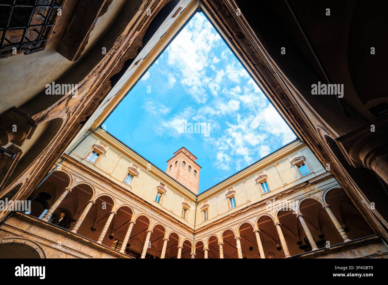 Bologna, Italia - Maggio 2026: Prospettiva geometrica ad angolo basso del cortile rinascimentale dell'Archiginnasio con doppia loggia che incornicia il cielo azzurro Foto Stock