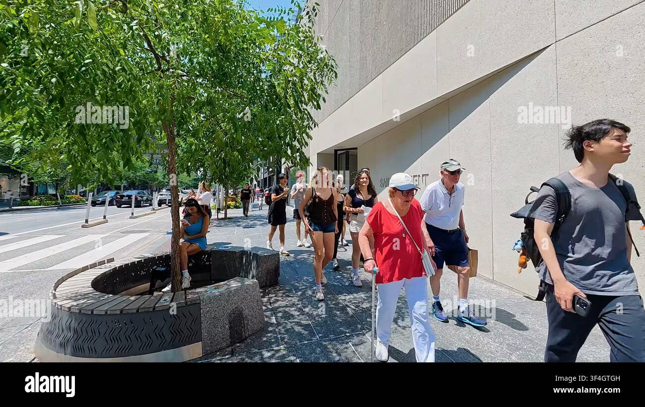 TORONTO, CANADA - 15 LUGLIO 2024: Diversi pedoni camminano lungo il marciapiede di cemento davanti a negozi di lusso su Bloor Street nel centro di Toronto, Canada. Foto Stock