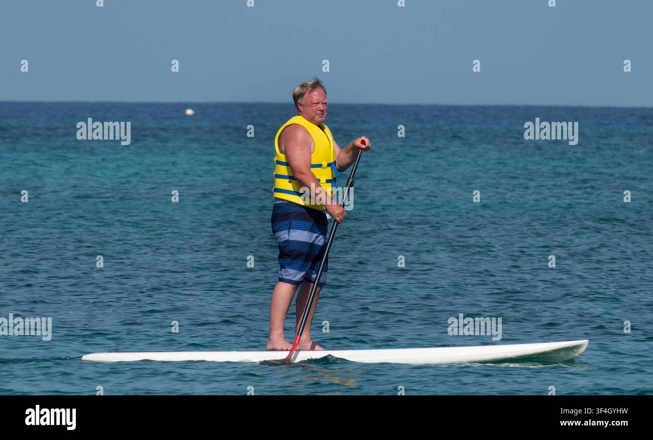 Una persona fa paddle boarding su un oceano calmo e blu. Foto Stock