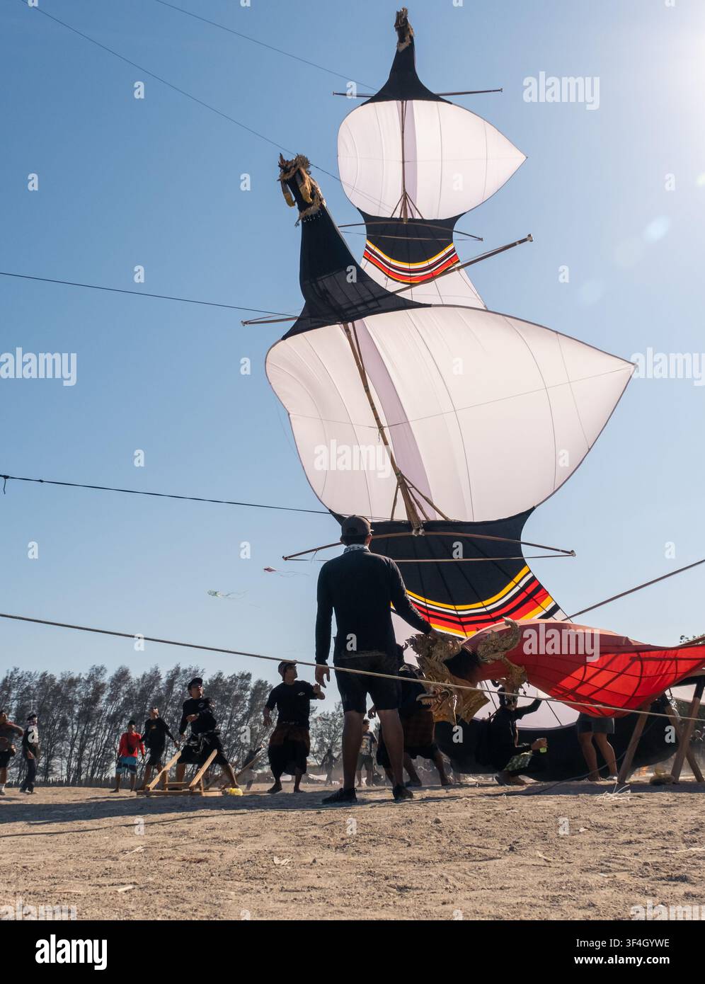 I volatori di aquiloni si preparano con cura per lanciare i loro aquiloni, lavorando insieme a Mertasari Beach, Sanur, Denpasar, Bali, il 25 luglio 2026. Foto Stock