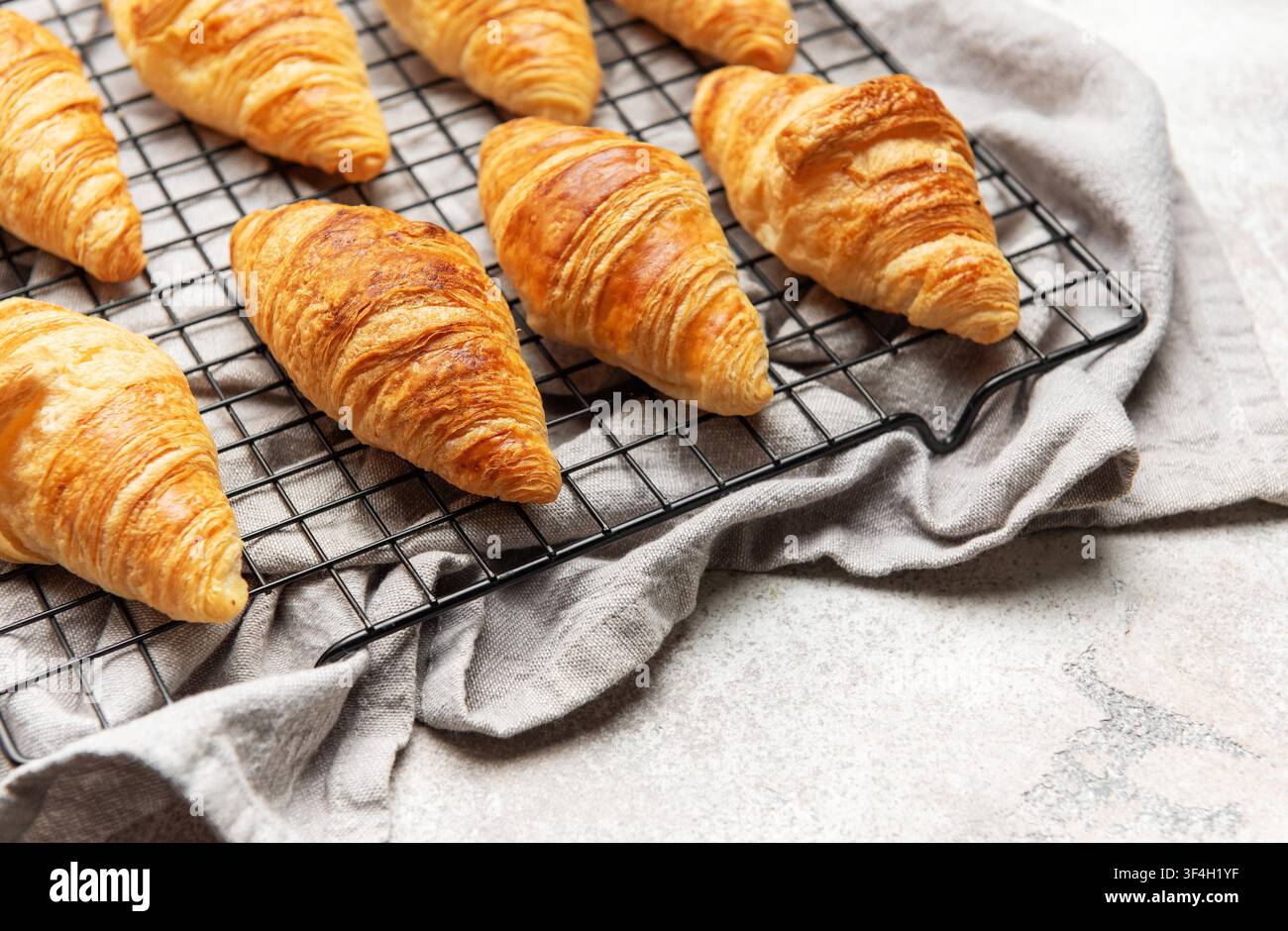 Croissant dorati appoggiati su una griglia metallica, creando un'allettante scena per la colazione Foto Stock