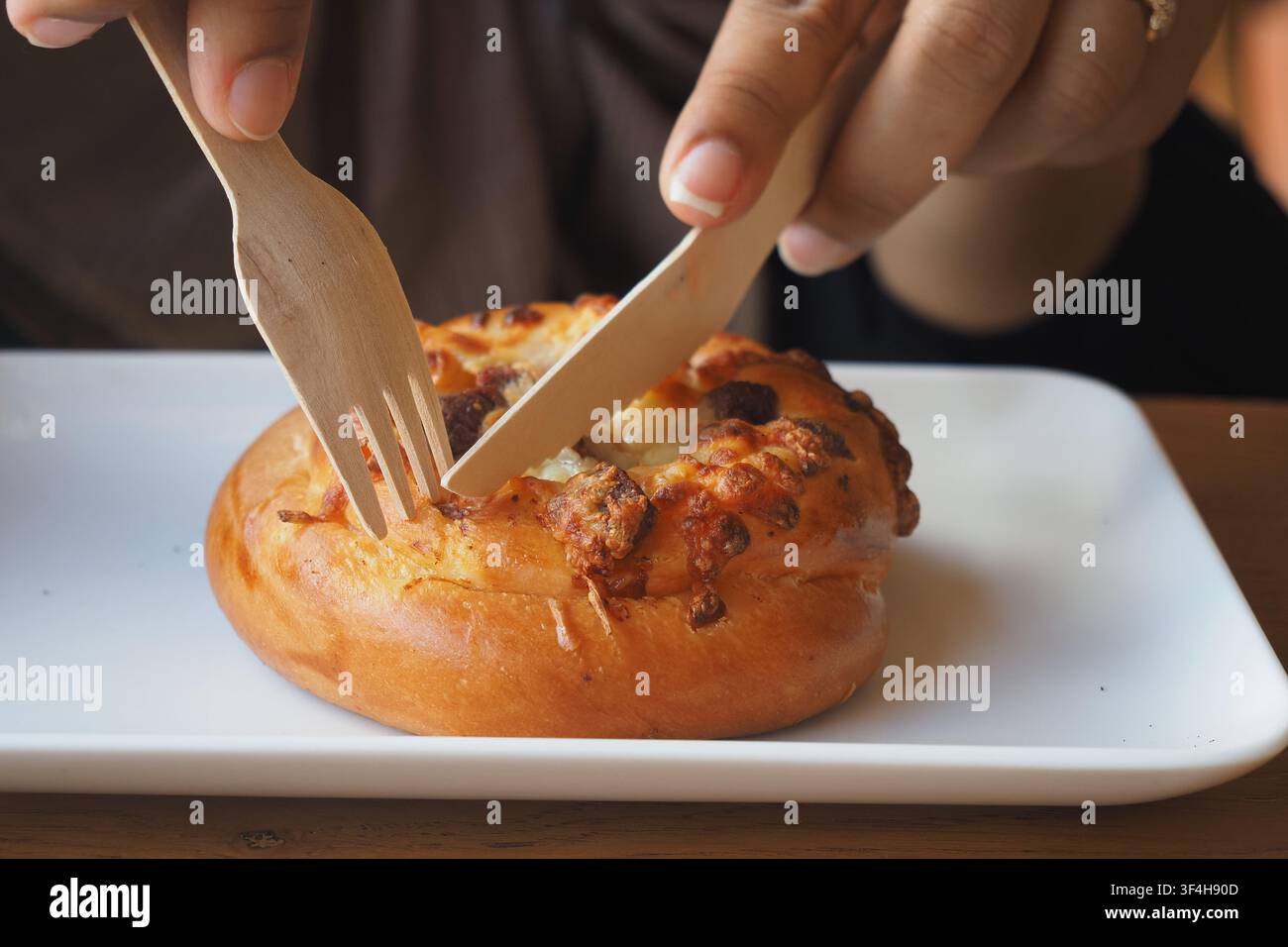 Persona taglia un dolce con utensili di legno Foto Stock