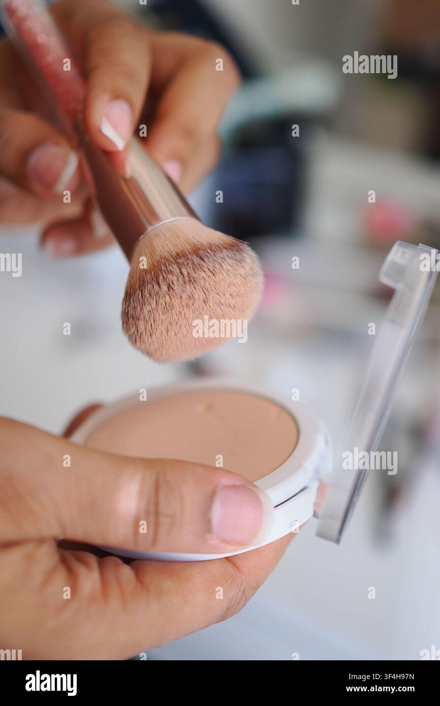 Applicare il trucco con un pennello e la polvere in una stanza Foto Stock