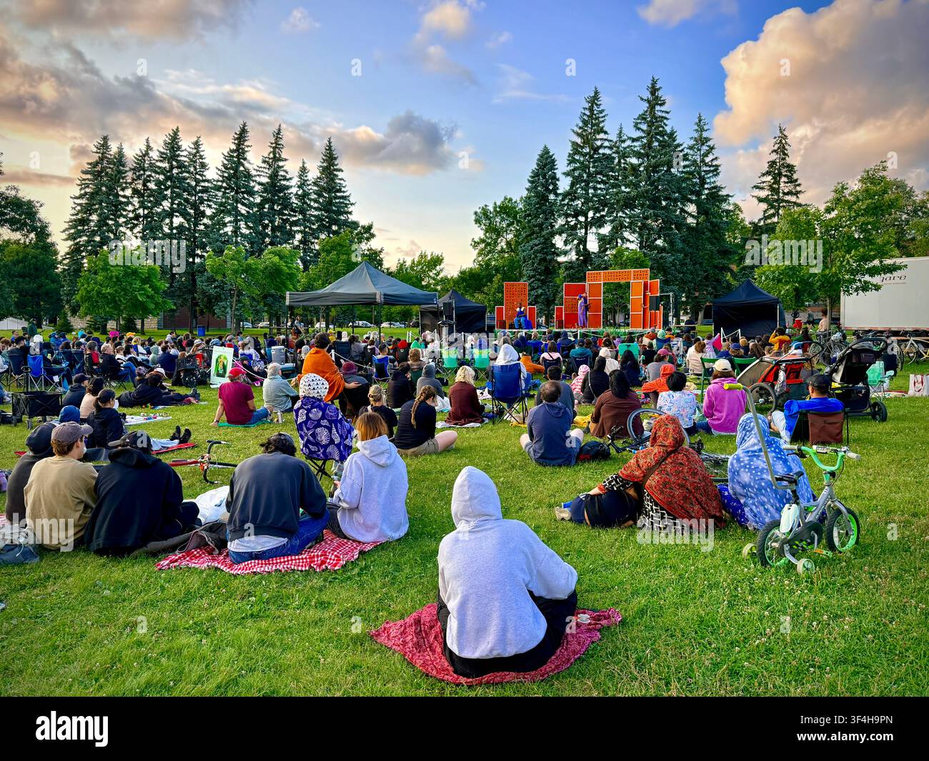 I membri del pubblico si radunano sull'erba per uno spettacolo all'aperto di Shakespeare nel parco al Jarry Park nel quartiere Villeray di Montreal, Canada - Immagine stock catturata con smartphone