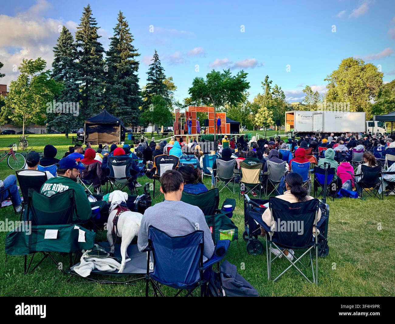 I membri del pubblico si radunano sull'erba per uno spettacolo all'aperto di Shakespeare nel parco al Jarry Park nel quartiere Villeray di Montreal, Canada - Immagine stock catturata con smartphone
