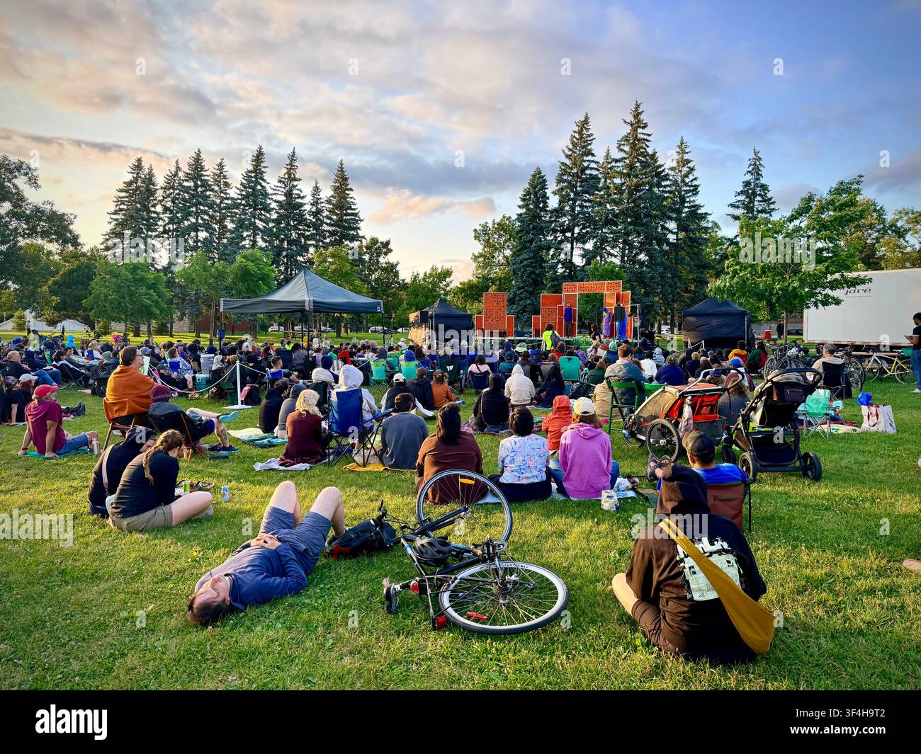 Gli spettatori si radunano sull'erba per una rappresentazione teatrale all'aperto di Shakespeare nel parco al Jarry Park nel quartiere Villeray di Montréal, Canada - Immagine stock catturata con smartphone