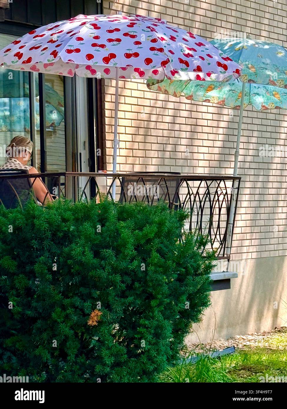 Ombrelli ombreggiano un balcone residenziale a Montréal, Québec, Canada, mostrando l'adattamento quotidiano al caldo estivo, all'esposizione al sole e al riscaldamento urbano Foto Stock
