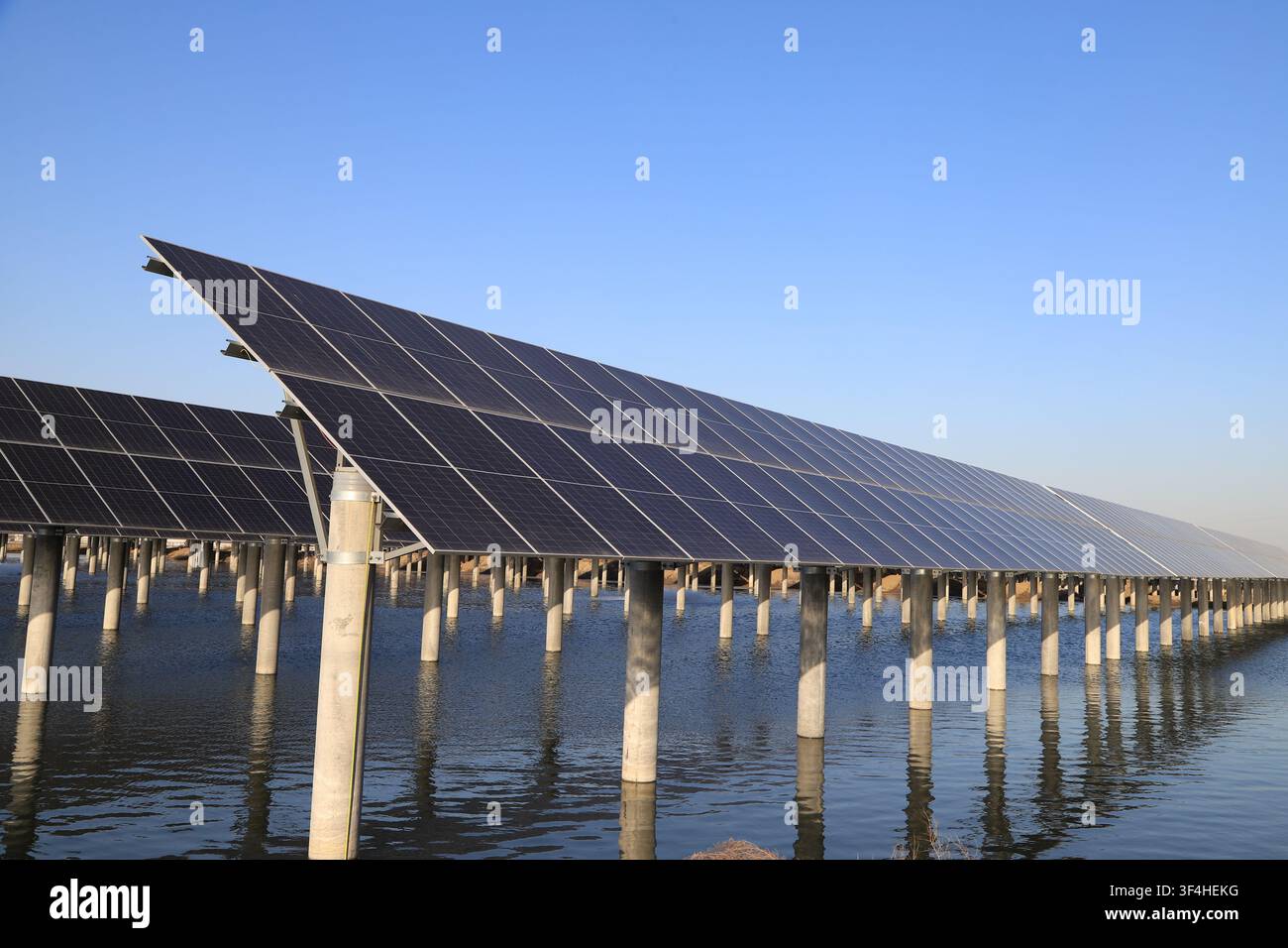 L'immagine presenta una vista simmetrica di una centrale solare galleggiante, con pannelli solari ordinatamente disposti su entrambi i lati sostenuti da pilastri in cemento. Foto Stock