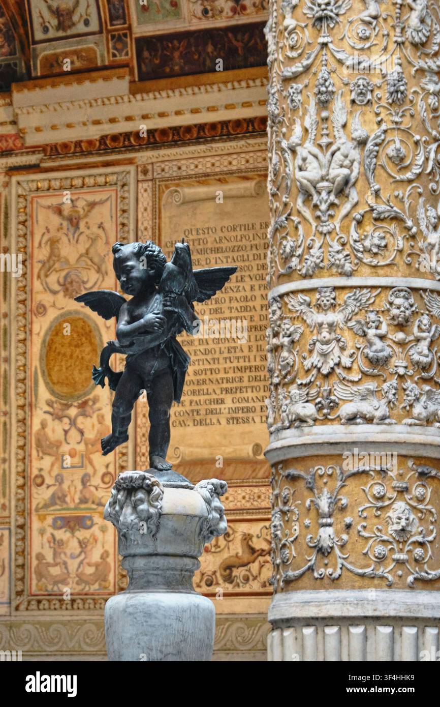 Firenze, Italia - Maggio 2026: Vista dettagliata della fontana Putto con delfino e della colonna stuccata all'interno del cortile del Palazzo Vecchio Foto Stock