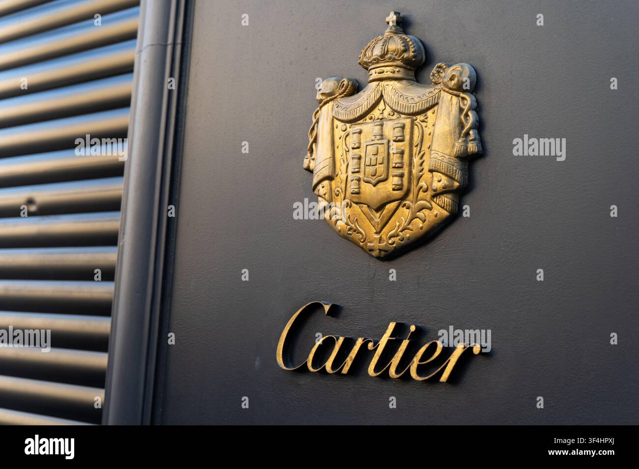 Marchio di lusso Cartier con logo dorato e segno dello stemma reale sulla parete esterna scura del negozio. Vienna, Austria - 21 giugno 2026 Foto Stock