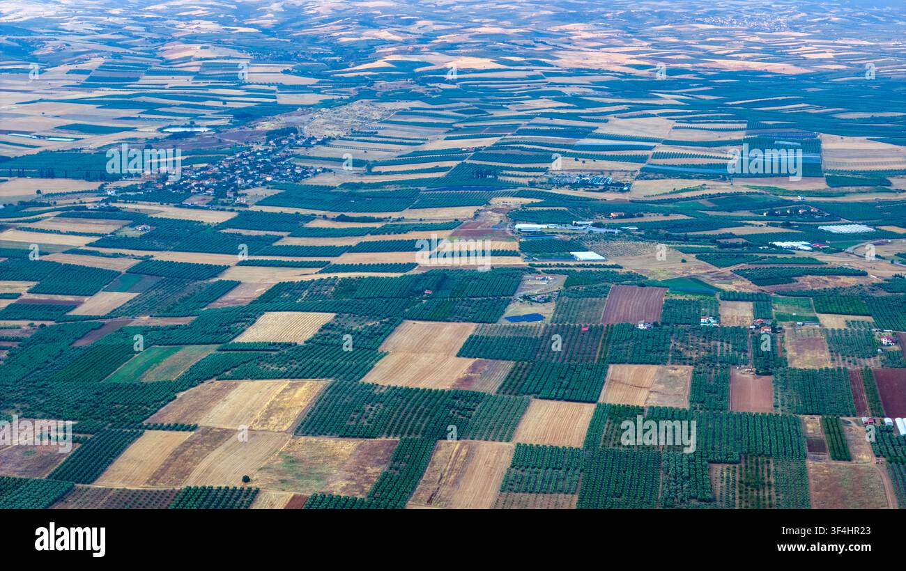 Una prospettiva aerea elevata rivela un mosaico geometrico di campi coltivati, frutteti e piccole insediamenti sparsi nella pianura vicino a Nea Moudania Foto Stock