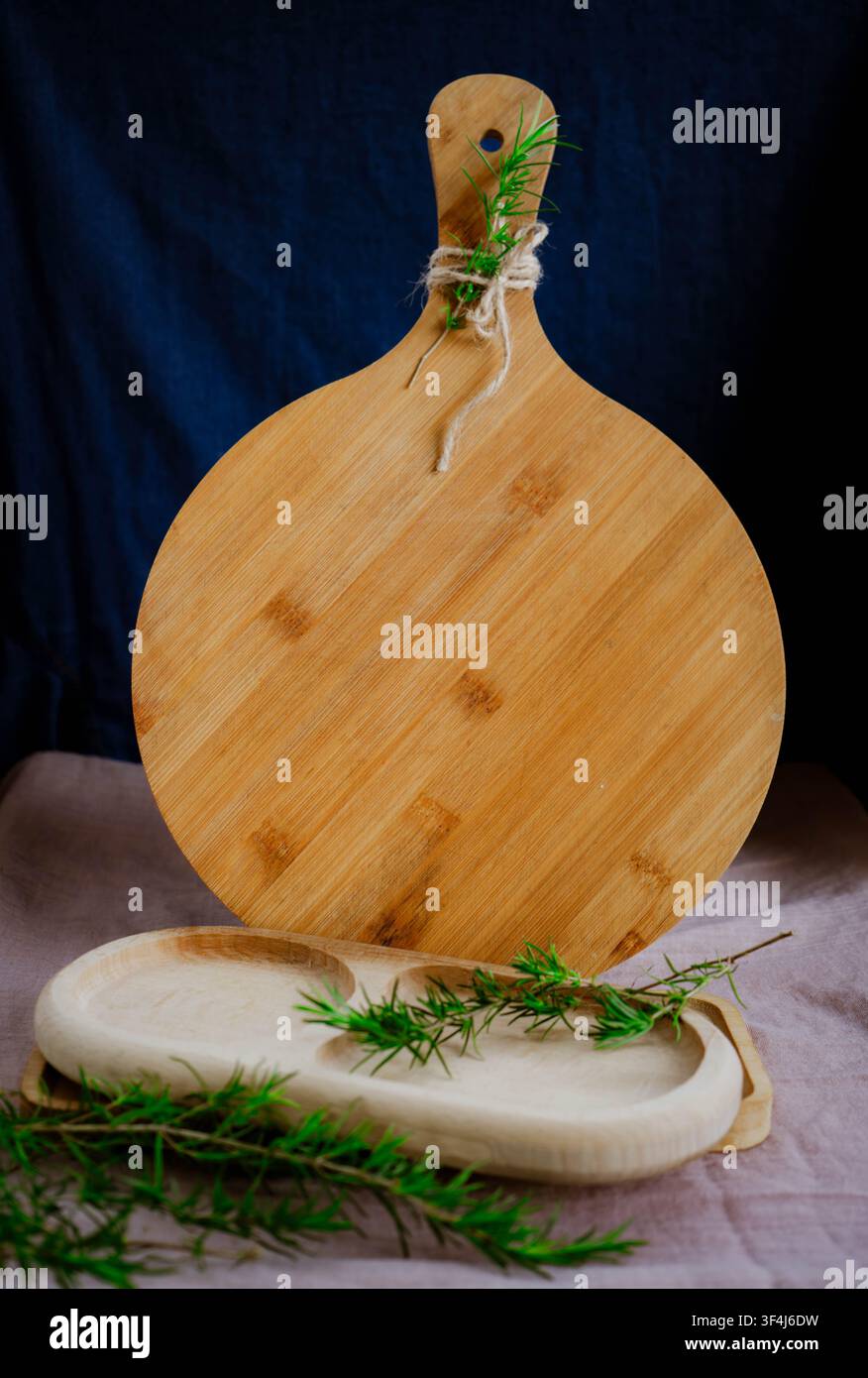 Vassoio da servizio in bambù vuoto con tre scomparti posizionato su un tagliere rotondo in legno sopra una stoffa di lino chiara. Stoviglie da tavolo minimali con copia Foto Stock