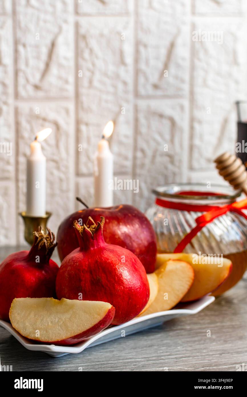 Arrangiamento di Rosh Hashanah con frutti simbolici e candele accese Foto Stock
