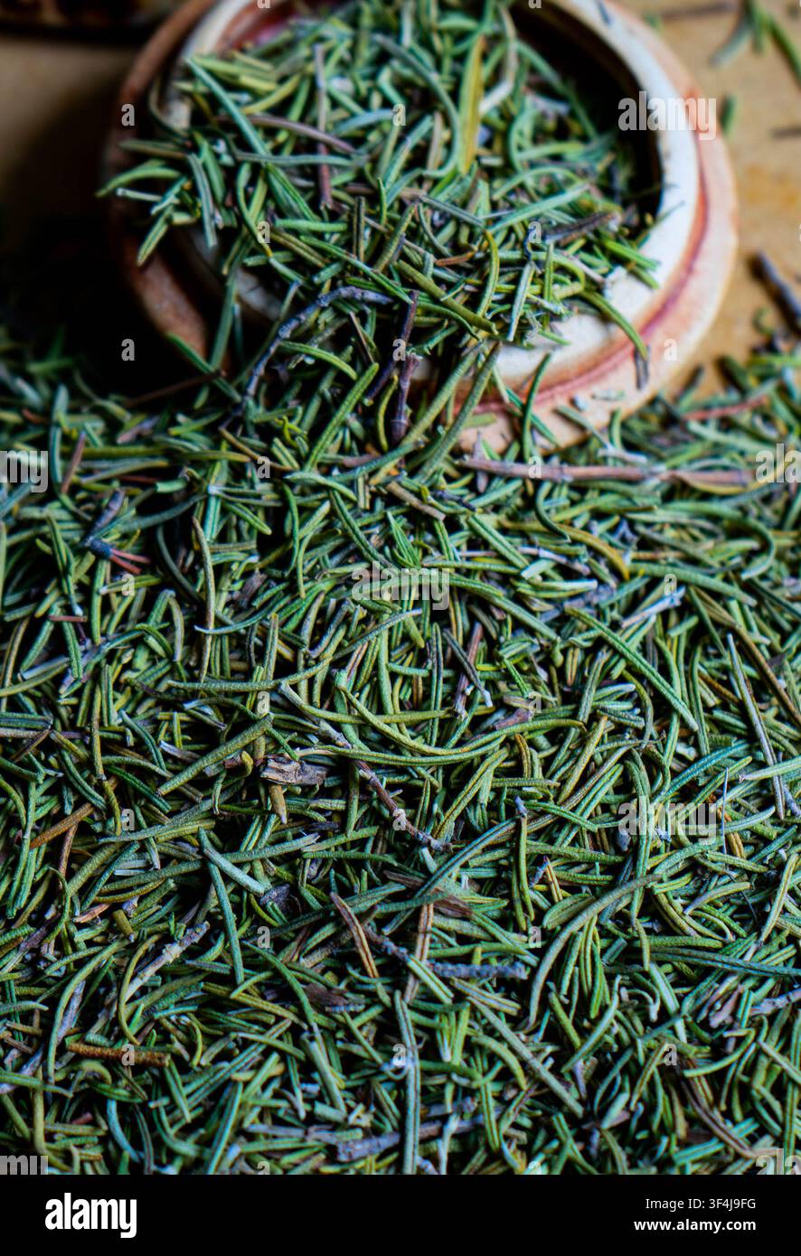Rametti di rosmarino fresco disposti su una superficie rustica. Erba aromatica utilizzata in cucina e nelle ricette salutari. Foto Stock