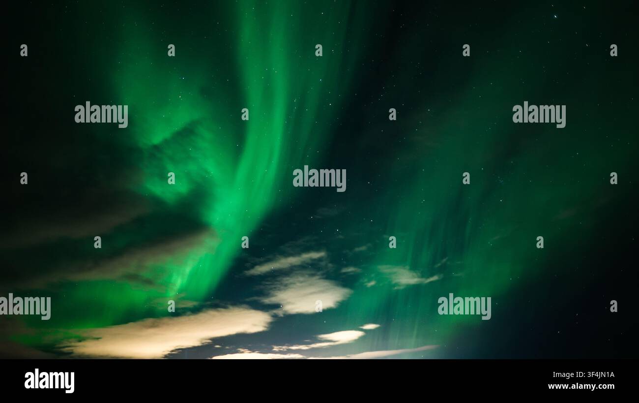 Aurore boreali verdi tra le nuvole in Islanda Foto Stock