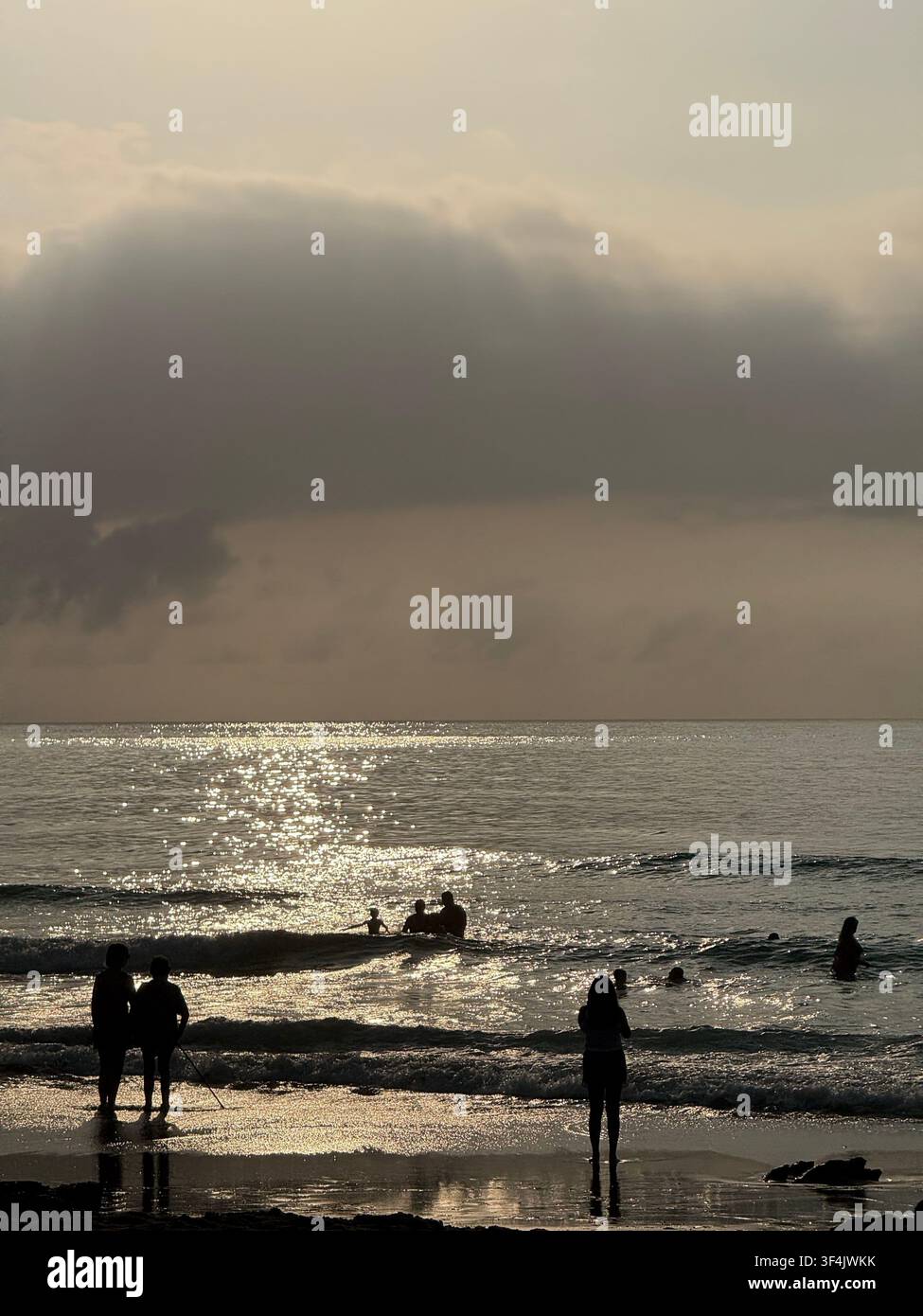 Persone in silhouette sulla costa atlantica sotto nuvole scure di pioggia al tramonto a Santander, Cantabria, Spagna - Immagine stock catturata con smartphone