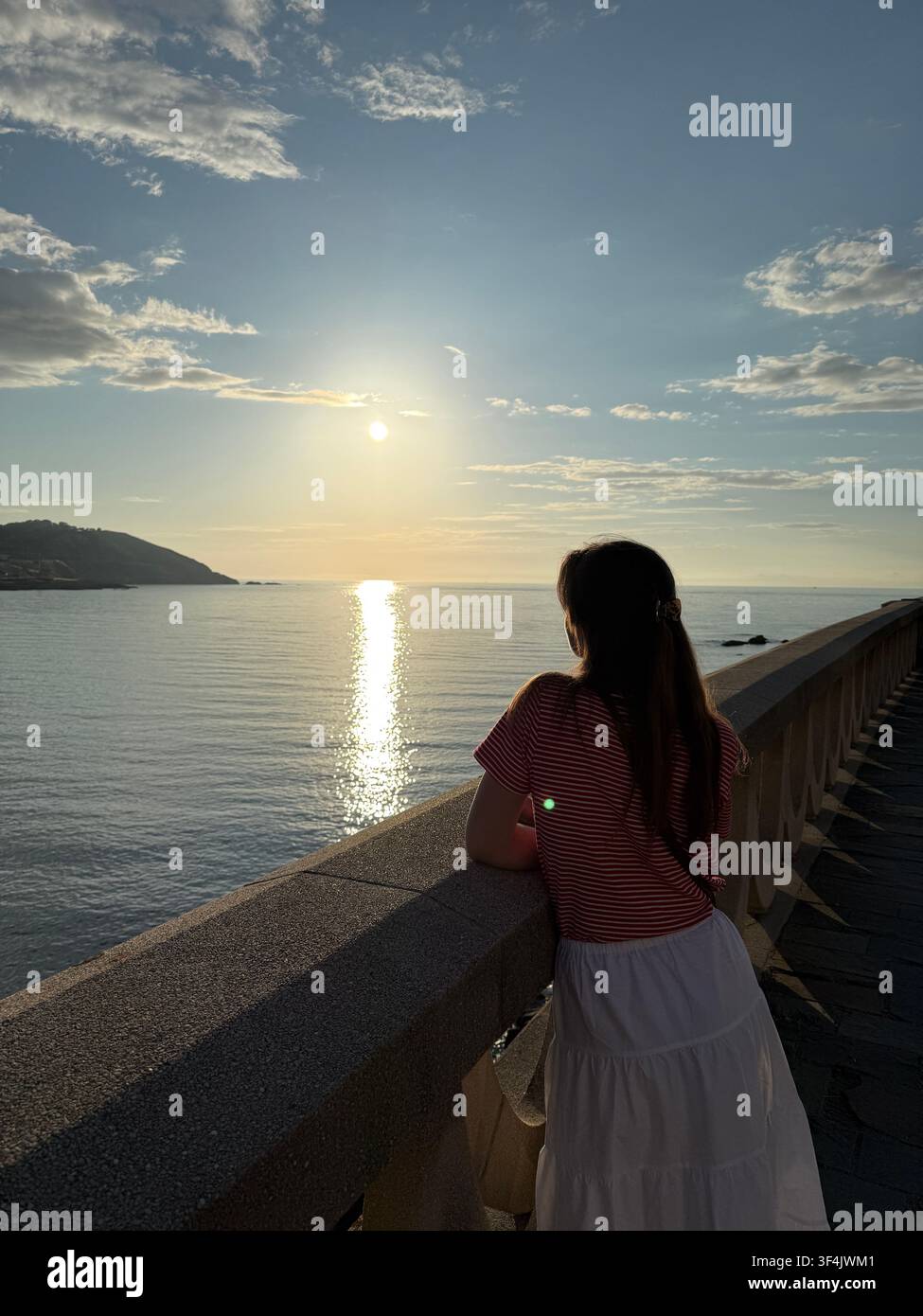 Donna che guarda l'Oceano Atlantico da una passeggiata costiera al tramonto ad A Coruña, Galizia, Spagna - Immagine stock catturata con smartphone