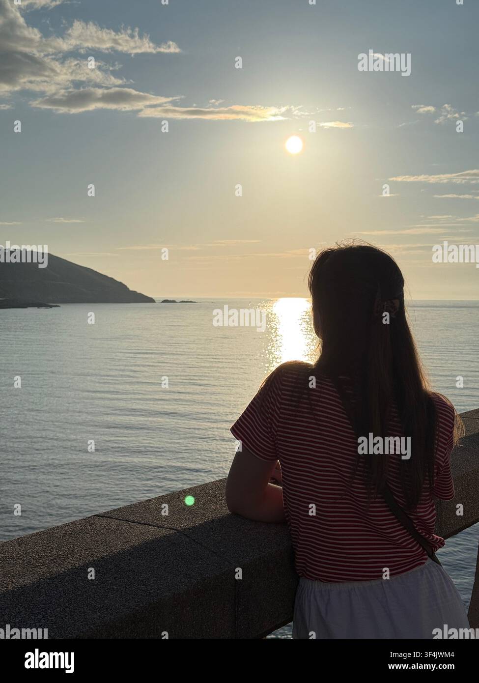 Donna che guarda l'Oceano Atlantico da una passeggiata costiera al tramonto ad A Coruña, Galizia, Spagna - Immagine stock catturata con smartphone