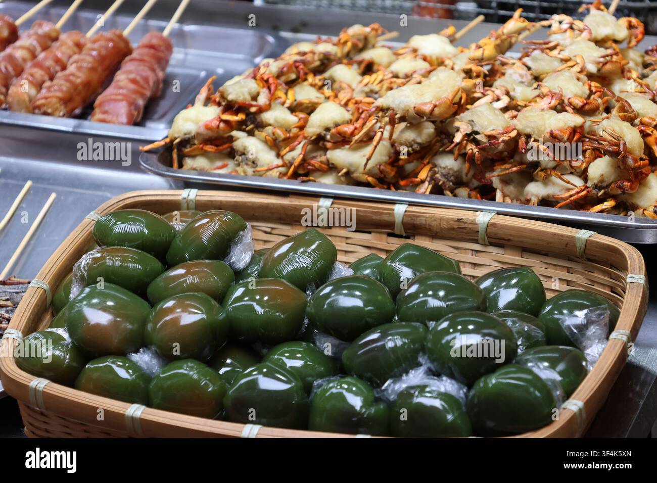 Tortini di riso glutinoso all’artemisia e granchi teneri fritti e salsiccia esposti in un mercato di strada della contea di Fenghuang, provincia di Hunan, Cina Foto Stock