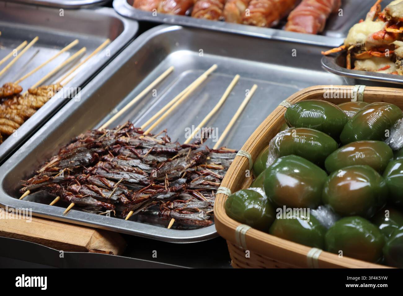 Cavallette fritte, tortini di riso glutinoso al mughetto, granchi dalla corazza molle fritti e salsicce esposti in un mercato di strada a Fenghuang County, Hunan, Cina Foto Stock