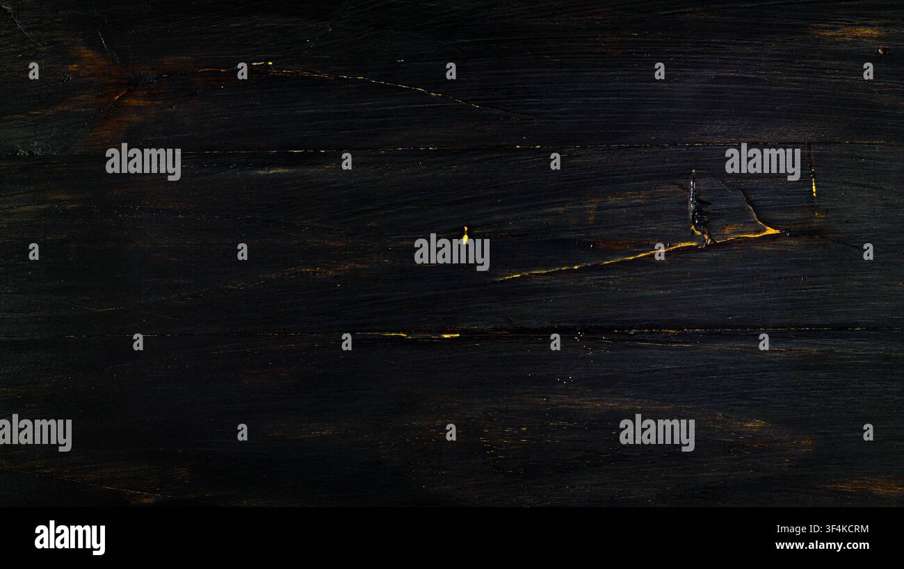 Sfondo in legno verniciato nero scuro con accenti naturali di venature dorate. Foto Stock