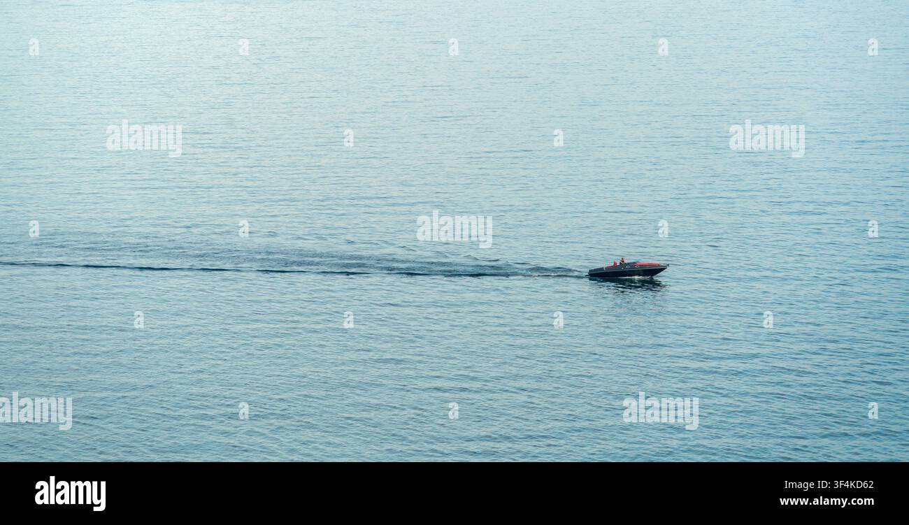 Barca a motore lontana sulla superficie dell'acqua Foto Stock