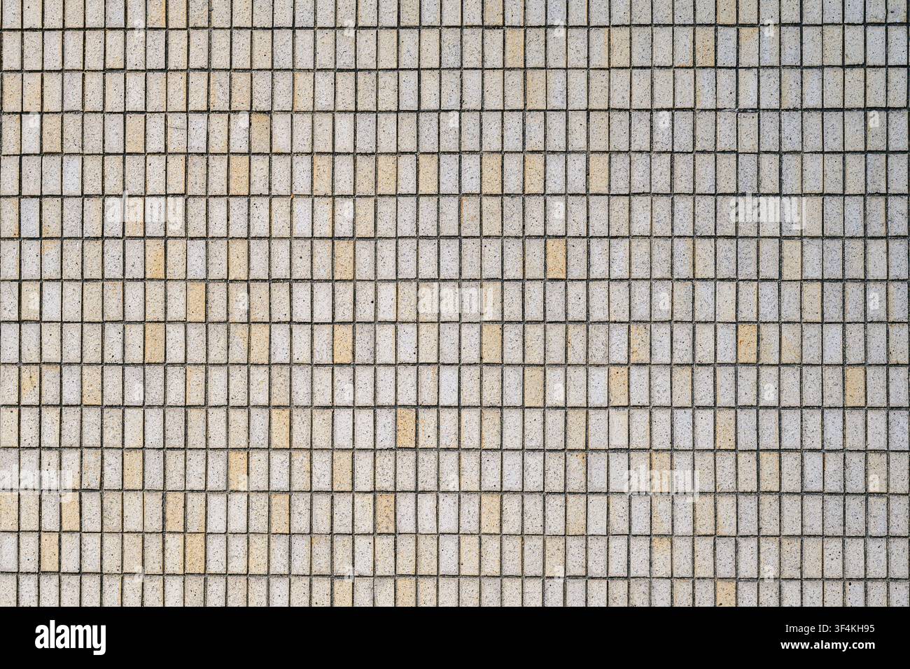 Piccole piastrelle di cemento formano una griglia ripetitiva sulla facciata di un edificio urbano Foto Stock
